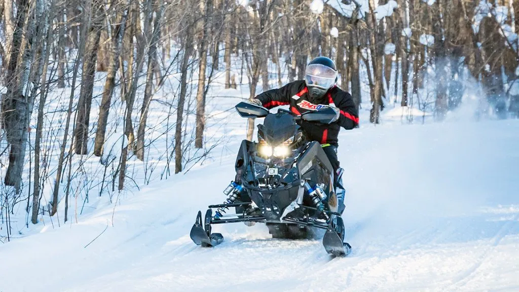 Snowmobile riding amongst trees AMSOIL shirt on the rider.
